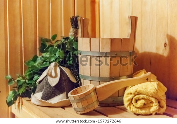 Interior details Finnish sauna steam room with\
traditional sauna accessories basin birch broom scoop felt hat\
towel. Traditional old Russian bathhouse SPA Concept. Relax country\
village bath concept