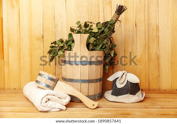 Interior details Finnish sauna steam room with\
traditional sauna accessories basin birch broom scoop felt hat\
towel. Traditional old Russian bathhouse SPA Concept. Relax country\
village bath concept