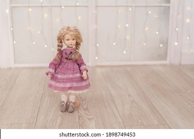 An interior doll with a human face, made by hand from textiles, in a retro style, stand on a light background garland lights. creating dolls for the holiday. an exclusive gift. Companion Doll