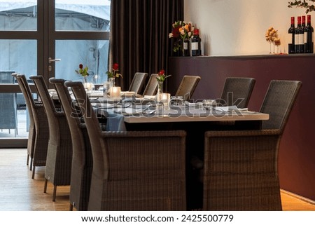 the interior of an elegant restaurant that exudes a warm atmosphere and style. Large panoramic windows let in plenty of natural light, illuminating the space. The interior is decorated in a minimalist