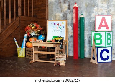 Interior Of Elementary School. Chalkboard, Backpack, Pencils And Stationery On Classroom. Back To School. Empty Classroom With Blackboard And Wooden Table. ABC Letters Alphabet On Wooden Cube Blocks 