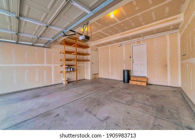 Interior Of Empty Attached Garage With White Door That Leads Inside The House