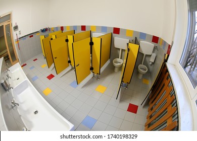 Interior Of Empty Bathroom Of A Daycare Center With Small Yellow Doors And White Ceramic Sink Photographed By Fisheye Lens Without Children