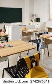 Interior of empty classroom with school desks and greenboard