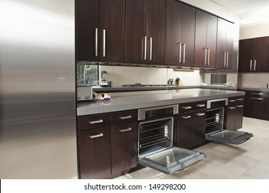 Interior Of Empty Commercial Kitchen With Open Oven And Cabinets