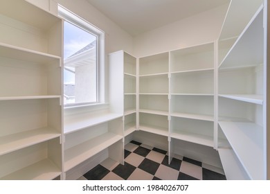 Interior Of An Empty Kitchen Pantry In A House With Window. There Are Wooden White Shelves On The Walls And A Chess Tile Flooring.