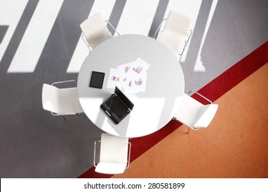 Interior Of Empty Office With Conference Tablet And Seat Without Men. Image From Above Of Conference Desk With Digital Tablet And Laptop. 