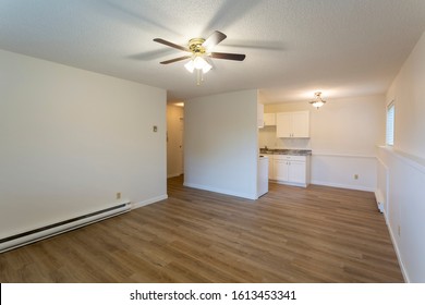 Interior of empty renovated apartment condo rental unit with white walls and new hard wood vinyl laminate flooring.