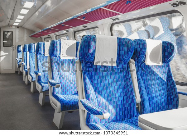 Interior of european first class passenger train\
with empty seats.