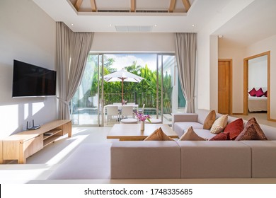 Interior And Exterior Design Of Living Room With Pool View In Luxury Pool Villa Feature Television, Sofa, Couch, Cushion, TV Console, Curtain And Sliding Door And Garden