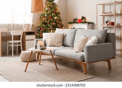 Interior of festive living room with grey sofa, coffee table and Christmas tree - Powered by Shutterstock