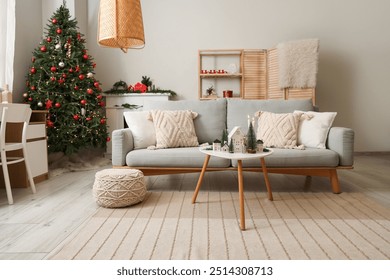 Interior of festive living room with grey sofa, coffee table and Christmas tree - Powered by Shutterstock