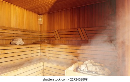 Interior of Finnish sauna, classic wooden sauna with hot steam. Russian bathroom. Relax in hot sauna with steam. Wooden interior baths, wooden benches and loungers accessories for sauna, spa complex.