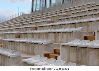 The interior of a football stadium without spectators. Seats for spectators on the stadium podium. Old worn plastic chairs for spectators of sports football matches