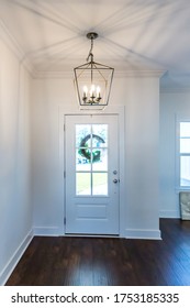 Interior Front Door Entrance Foyer With Hardwood Flooring And A Hanging Light Fixture 