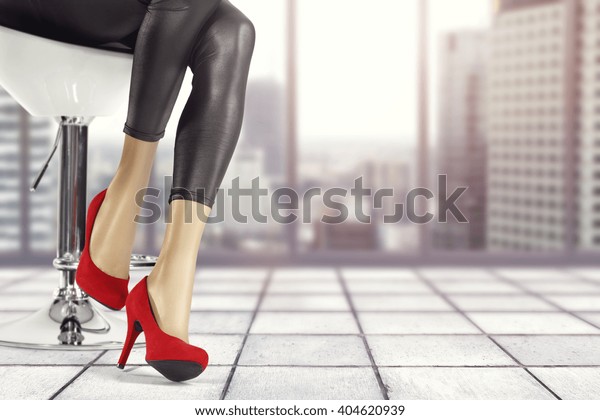 interior of gray floor and window and slim woman legs\
and red heels 
