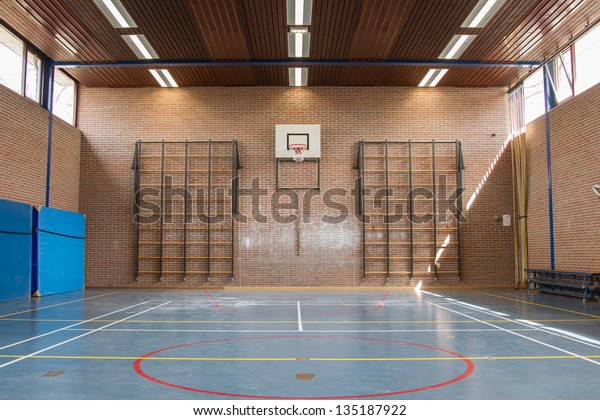 Interior\
of a gym at school, jumping high at the\
basket