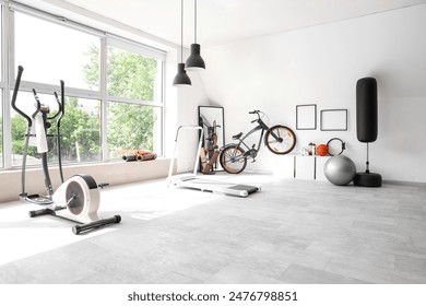 Interior of gym with sports equipment, bicycle and mirror