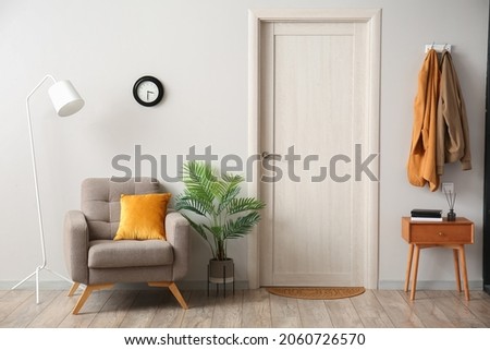 Interior of hallway with armchair, table and door mat