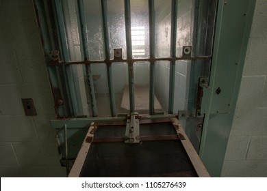 Interior Of High Risk Solitary Confinement Cell With Concrete Bed And Door With Metal Bars.