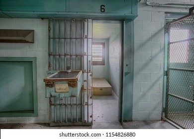 Interior Of High Risk Solitary Confinement Cell With Concrete Bed And Door With Metal Bars.