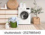 Interior of home laundry room with washing machine, chest of drawers, houseplants and basket with clothes