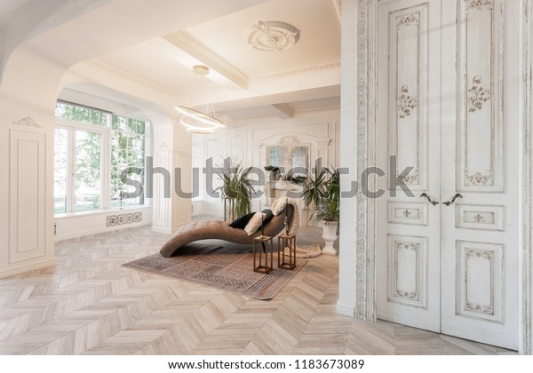 interior in hotel. daylight\
in the interior and light of electric lamps. luxury living room\
with parquet wood floors, fireplace, sofa and houseplant. Stucco on\
walls