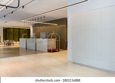Interior of a hotel lobby with reception desks with transparent covid plexiglass lexan clear sneeze guards - Shutterstock ID 1802116888