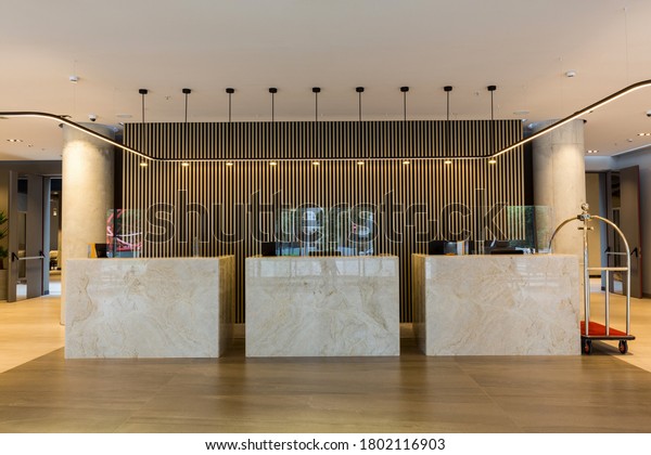 Interior of a hotel\
lobby with reception desks with transparent covid plexiglass lexan\
clear sneeze guards
