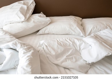 Interior Of Hotel Room In The Morning With Messy Bed. Crumpled White Bed Linen, Pillows And Blanket On The Bed 