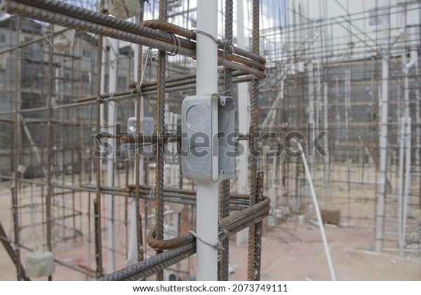 Interior of house under\
construction of electrical base with pipes and steel rods\
supporting the house.