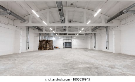 The interior of a huge industrial warehouse made of white bricks with a high ceiling for storing goods. The concept of storage of goods by importers, exporters, wholesalers, transport enterprises
