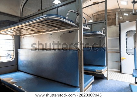 Interior of an Indian Railways sleeper class coach featuring blue berths, luggage racks, and passenger seating, showcasing affordable rail travel, public transportation, and railway infrastructure in India.