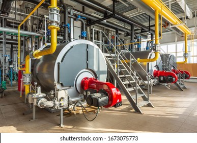 The interior of an industrial boiler room with three large boilers, many pipes, valves and sensors. - Shutterstock ID 1673075773
