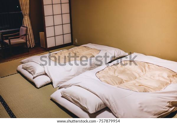 interior inside the\
bedroom of old style Japanese Ryokan room with white futon mattress\
on the tatami mat