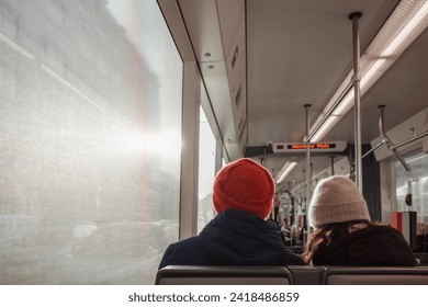 Interior inside tram and back view of couple passenger wear beanie sit next each other against sunlight.  - Powered by Shutterstock