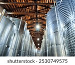 The interior of Kindzmarauli Winery displays stainless steel fermentation tanks used for wine production in Georgia.