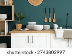 Interior of kitchen with counters with different plates near blue wall