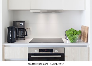 The Interior Of The Kitchen With Electric Appliances, Hood, Kettler, Coffee Maker, Stovetop And Oven