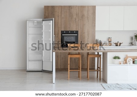 Interior of kitchen with empty fridge, table and counters