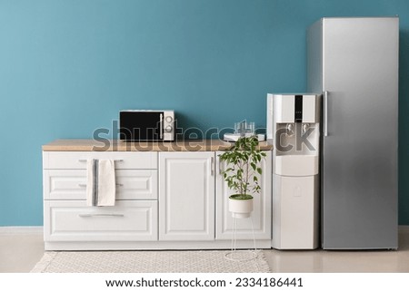Interior of kitchen with modern water cooler near blue wall