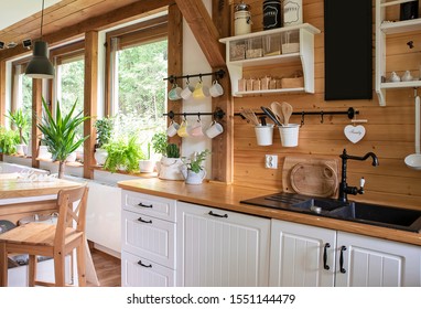 Interior of kitchen in rustic style with vintage kitchen ware and window. White furniture and wooden decor in bright indoor. Country style.