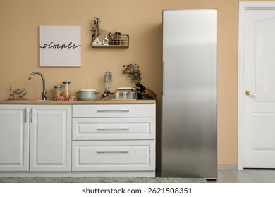 Interior of kitchen with silver fridge, counters and shelf