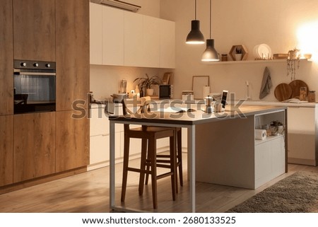 Interior of kitchen with table, counters and glowing lamps in evening