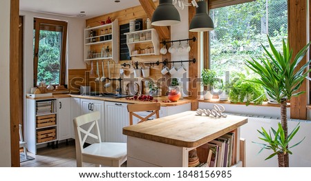 Interior of kitchen in vintage rustic style with wooden furniture in a cottage. Bright indoors in a cozy kitchen with window and plant. 