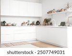 Interior of kitchen with white counters, shelf and utensils