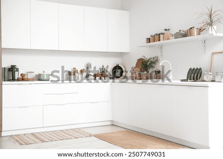 Interior of kitchen with white counters, shelf and utensils