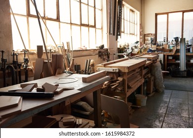 Interior of a large woodworking shop with workbenches full of an assortment of cut wood and tools - Shutterstock ID 1615984372