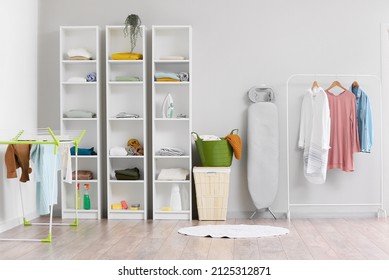 Interior Of Laundry Room With Dryer, Shelf Units, Baskets And Rack With Clothes