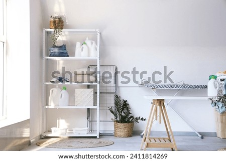 Interior of laundry room with ironing board and cleaning supplies on shelving unit